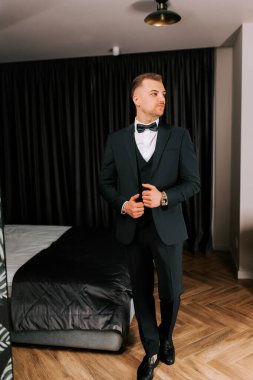 Stylish man in formal attire poses confidently in a modern bedroom setting