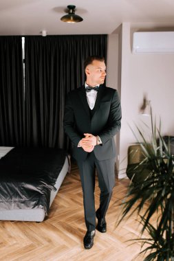 Man dressed in formal attire prepares for a special event in a stylish modern room