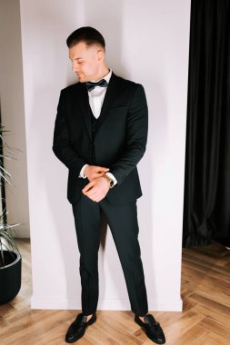 Man in formal suit strikes a pose in a modern indoor setting during a special event