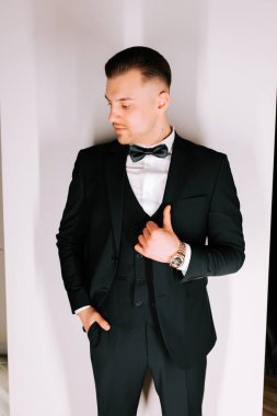 Stylish man in tuxedo posing confidently against a minimalist background