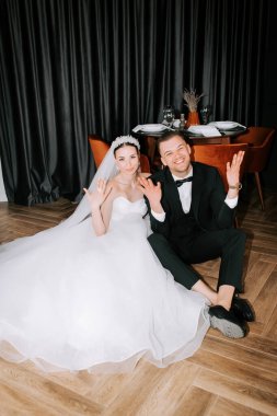 Couple celebrates their wedding day with joyful poses in an elegant indoor setting
