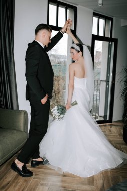 Couple dances joyfully in wedding attire inside modern venue during celebration