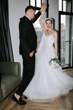 Couple celebrating their wedding day indoors with elegant attire and joyful dance