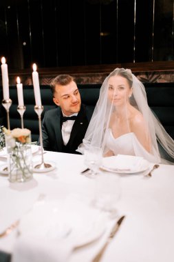 Couple celebrates their wedding reception at an elegant restaurant with candles and soft lighting