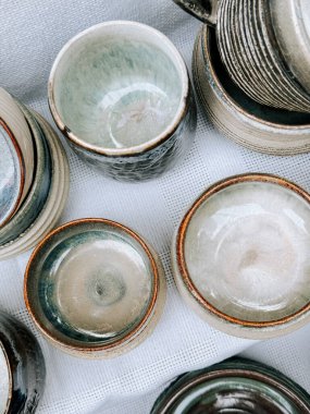 El yapımı çömlek kaseleri ve fincanlar bir el işi pazarında beyaz bir beze dizilmiş.