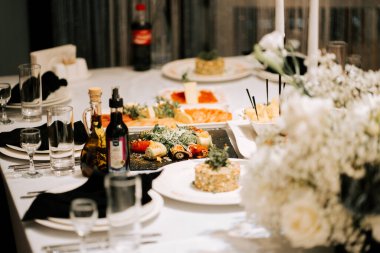 Bir kutlama toplantısında gurme yemekleri ve çiçek aranjmanları sunan zarif bir yemek takımı.