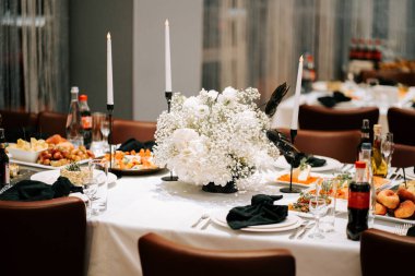 Modern bir mekanda çiçek süsü ve çeşitli yemekler ile şık bir yemek düzeni.