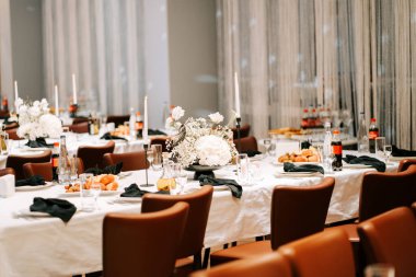 Çiçek süslemeleri ve resmi bir toplantı için hazırlanan yiyeceklerle şık bir yemek düzeni.