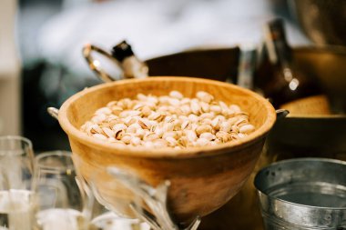 Modern bir sosyal toplantıda ahşap bir kasede servis edilen taze kabuklu fıstıklar.