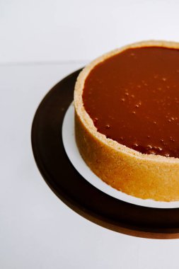 Kahverengi bir tabağa beyaz bir arka planı olan lezzetli çikolatalı tart.