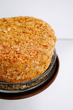 Parlak bir ortamda cam bir tabakta kırıntı kaplı katmanlı pasta.