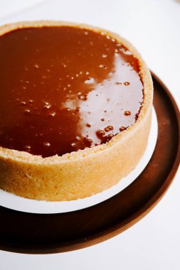 Ahşap servis tabağında parlak bir kapağı olan lezzetli karamel tartı.