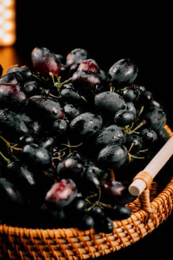 Olgun üzümler bir sepetin içinde toplanmış zengin renklerini ve tazeliklerini sergiliyorlar.