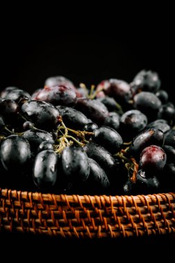 Hasat edilmiş taze üzümler hasır sepetin içinde güzelce yerleştirilmiş.