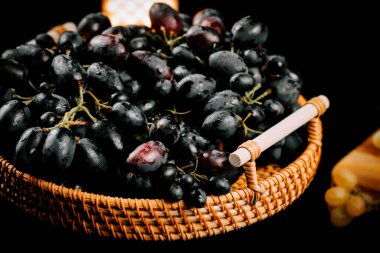 Sıcak bir ortam için yumuşak ışıklandırmayla dokuma sepetine yerleştirilmiş taze üzümler.