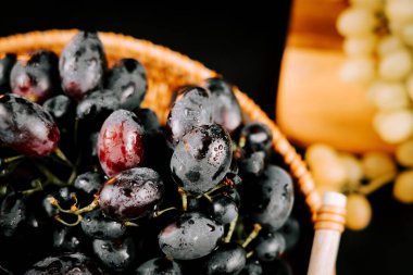 Dokuma sepetinde olgun üzümler, su damlacıkları ve yakın kümeler.