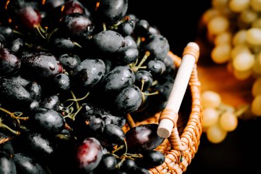 Olgun üzümler hasır bir sepette sergileniyor güneş ışığı tazeliklerini vurguluyor.