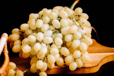 Olgun üzümler bir üzüm bağından toplanır ve ahşap bir tahtanın üzerinde sergilenir.