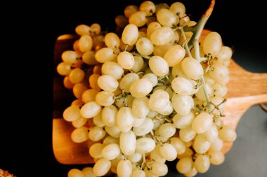 Ahşap bir yüzey üzerinde olgun üzümler. Mutfak ortamında hasat ve tüketime hazır.