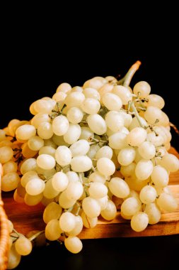 Olgun yeşil üzümler, tahta yüzeyde koyu arkaplanda sergilenir.