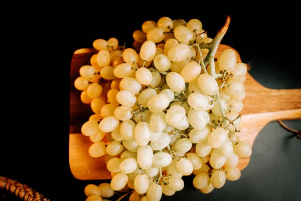 Olgun üzümler, güneşli bir günde hasat edilmeye hazır ahşap bir tepside dizilmiştir.