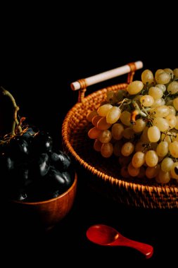 Olgun üzümler, yakınlarda servis edilecek küçük bir kaseyle dokuma sepetinde sergilenir.