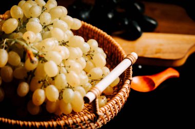 Taze toplanmış olgun üzümler yakınlarda koyu üzümlerle dokunmuş bir sepetin içinde sergileniyor.