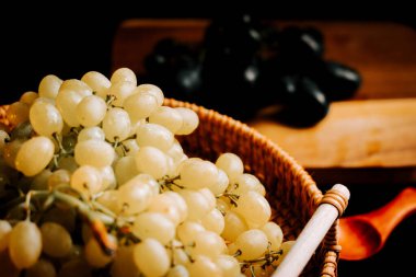 Taze üzümler dokuma sepetinde güneşli bir üzüm bağından toplanmaya hazır.