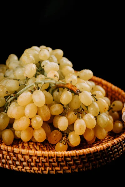 Olgun yeşil üzümler örülmüş sepetin içinde koyu bir arka planda