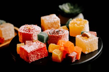 Lokum siyah bir tabakta zarif bir şekilde sergilenmiş renkli Türk zevkleri dizisi