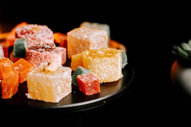 Lezzetli dokuları ve tatları vurgulayan siyah bir tabağa dizilmiş renkli Türk lezzetleri