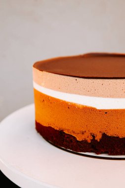 Zengin çikolata ve kremsi dokuları olan renkli katmanlı pasta kaidede sergilenir.