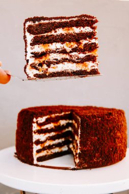 Sıcak bir mutfak ortamında beyaz bir kaidede servis edilen lezzetli katmanlı çikolatalı pasta.