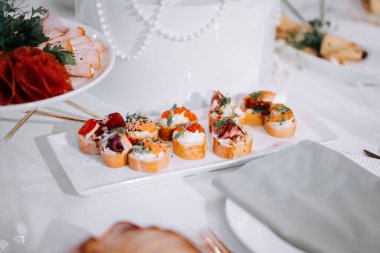 Lezzetli aperatifler şık bir ortamda beyaz bir tabakta sunuluyor.