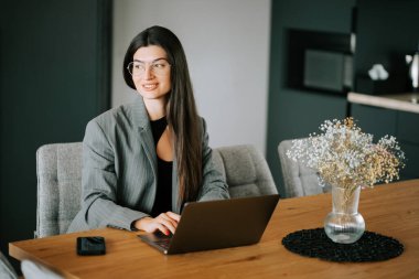 Evden çalışan genç bir profesyonel. Kapalı bir çalışma alanında dizüstü bilgisayarla çalışıyor.