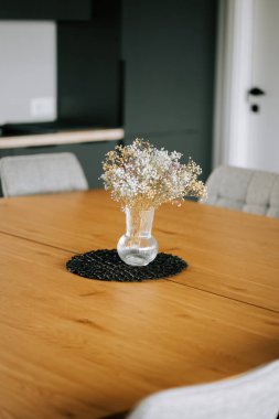 Ahşap bir masada vazosu olan parlak ve rahat bir yemek salonu.