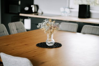 Modern bir mutfak ortamında, ahşap bir masa ve rahat bir atmosferi olan taze çiçekler.