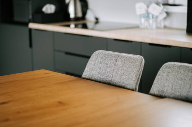 Gri sandalyeli modern mutfak ve rahat bir ev ortamında ahşap masa.