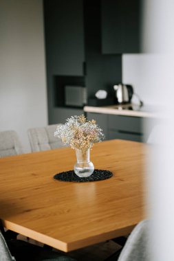 Ahşap bir masa ve bir vazo kurumuş çiçekle modern yemek odası.