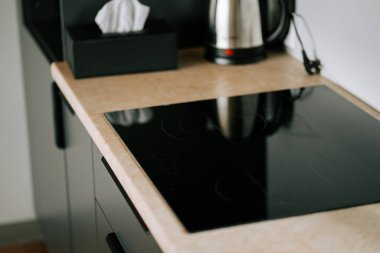 Modern mutfak tezgahı elektrikli ocak ve kahve ısıtıcısının yanında minimalist dekor.