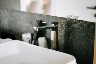 Modern banyo lavabosu, şık musluk ve düzgün düzenlenmiş banyo takımları.