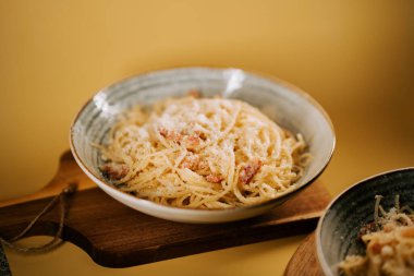 Samimi bir ortamda ahşap bir tahtanın üzerinde rustik bir kasede servis edilen leziz makarna bolonez.