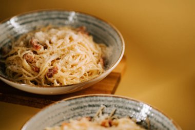 Basit bir ahşap masada peynirli makarna.