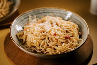 Tahta bir masada kırsal bir kasede servis edilen leziz bolonez makarna.