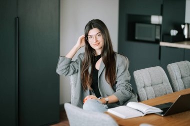 Ahşap masada otururken modern ofiste çalışan profesyonel bir kadın.