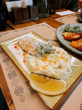 Samimi bir restoran ortamında patates püresi ve sebzeyle servis edilen lezzetli somon tabağı.