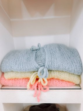 Yumuşak pastel süveterler hoş bir butiğin rafında düzgünce yerleştirilmiş.