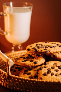 Sıcak bir ortamda bir bardak soğuk sütle servis edilen lezzetli çikolatalı kurabiyeler.