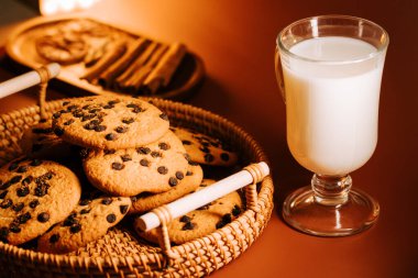 Sıcak bir ortamda soğuk sütle servis edilen taze pişmiş çikolatalı kurabiyeler.