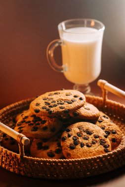 Taze pişmiş çikolatalı kurabiyeler ve bir bardak süt.
